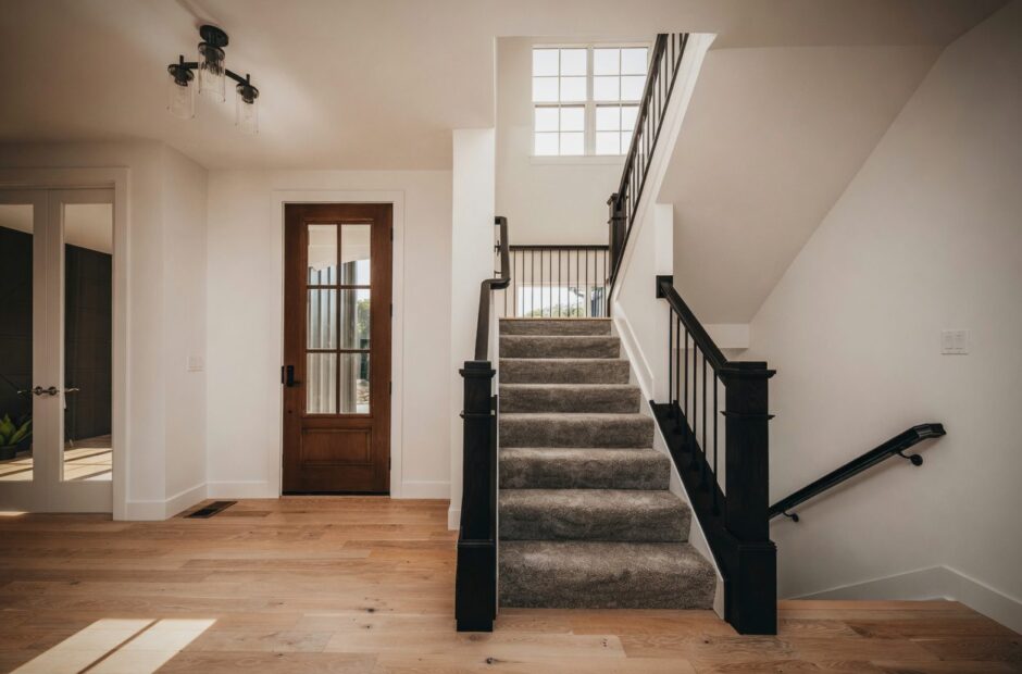 Cypress Pointe floor plan entryway with wood front door, light hardwood floors, and carpeted staircase with black iron railing — Justin Doyle Homes, Cincinnati