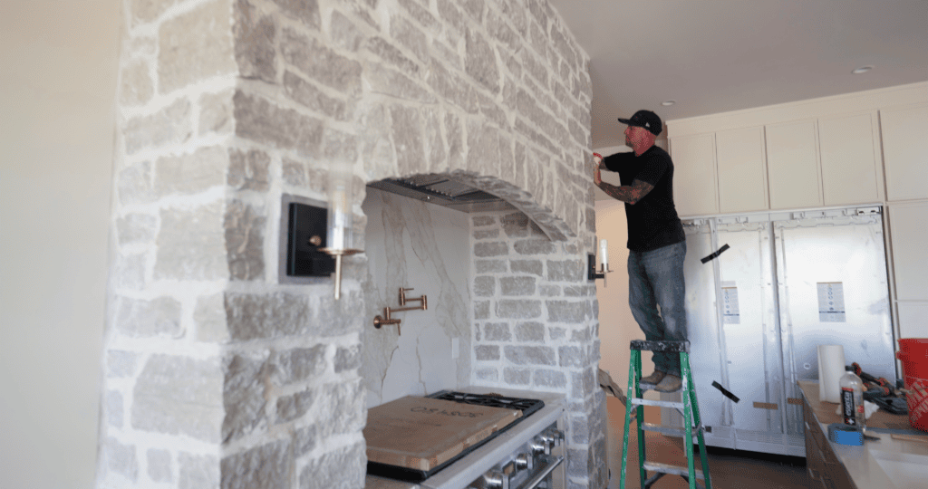 Mason finishing the stone arch above the range hood in the kitchen of The Ironwood by Justin Doyle Homes