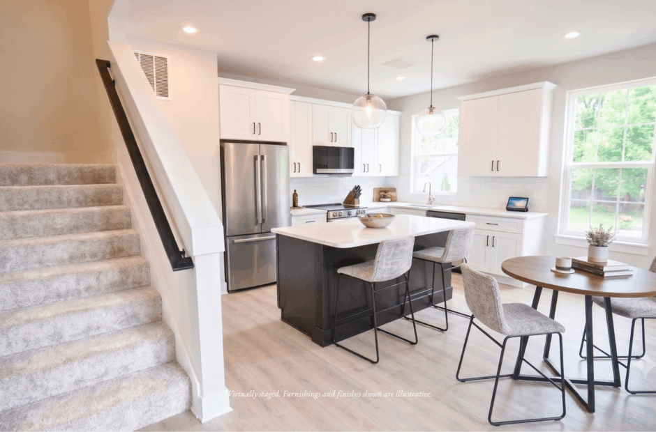 Open kitchen, dining area, and carpeted staircase in a Lebanon Landing 3 bedroom townhome, with white cabinets, dark island, and quartz countertops.