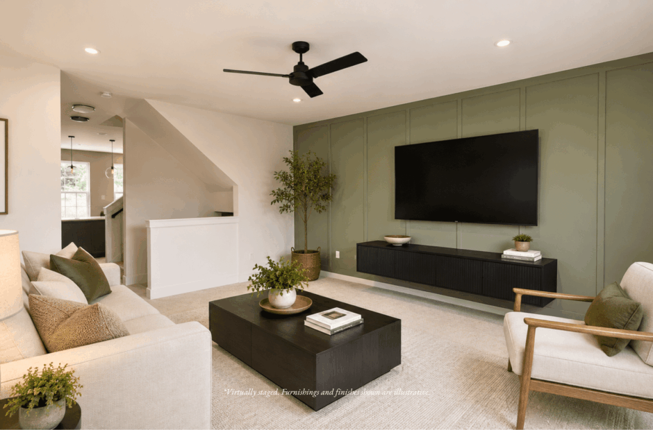 Living room in a Lebanon Landing 2 bedroom townhome featuring a sage green board-and-batten accent wall, neutral furnishings, and pass-through to the kitchen.