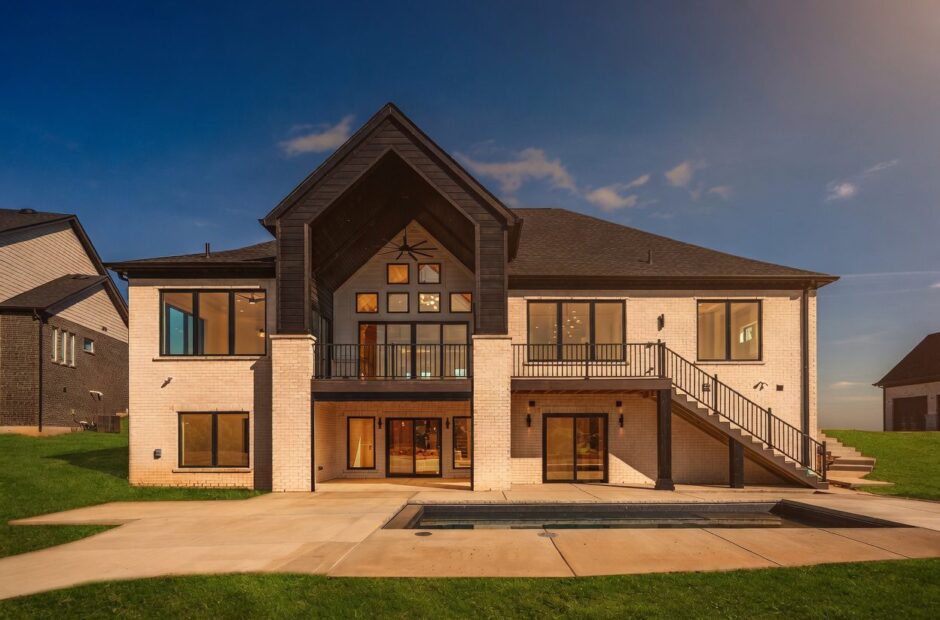 Breckenridge rear exterior at dusk with upper deck, walkout lower level, pool, and warm interior lighting by Justin Doyle Homes — custom home builder Cincinnati