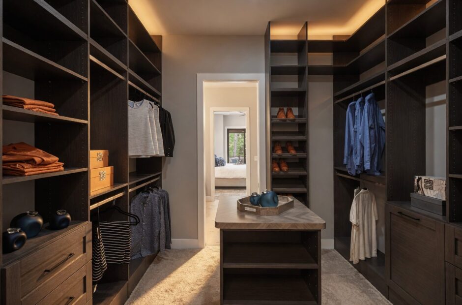 Oakmont floor plan primary suite walk-in closet with dark built-in shelving, center island, LED cove lighting, and direct access to bedroom — Justin Doyle Homes, Cincinnati