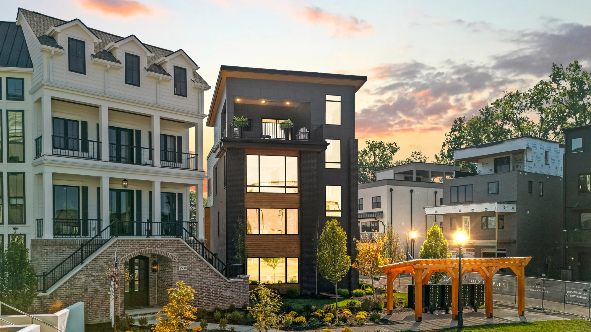 The Obsidian, a four-story Justin Doyle Homes home of black brick, dark panel and cedar, at dusk with its windows lit at Foundry Park in Oakley