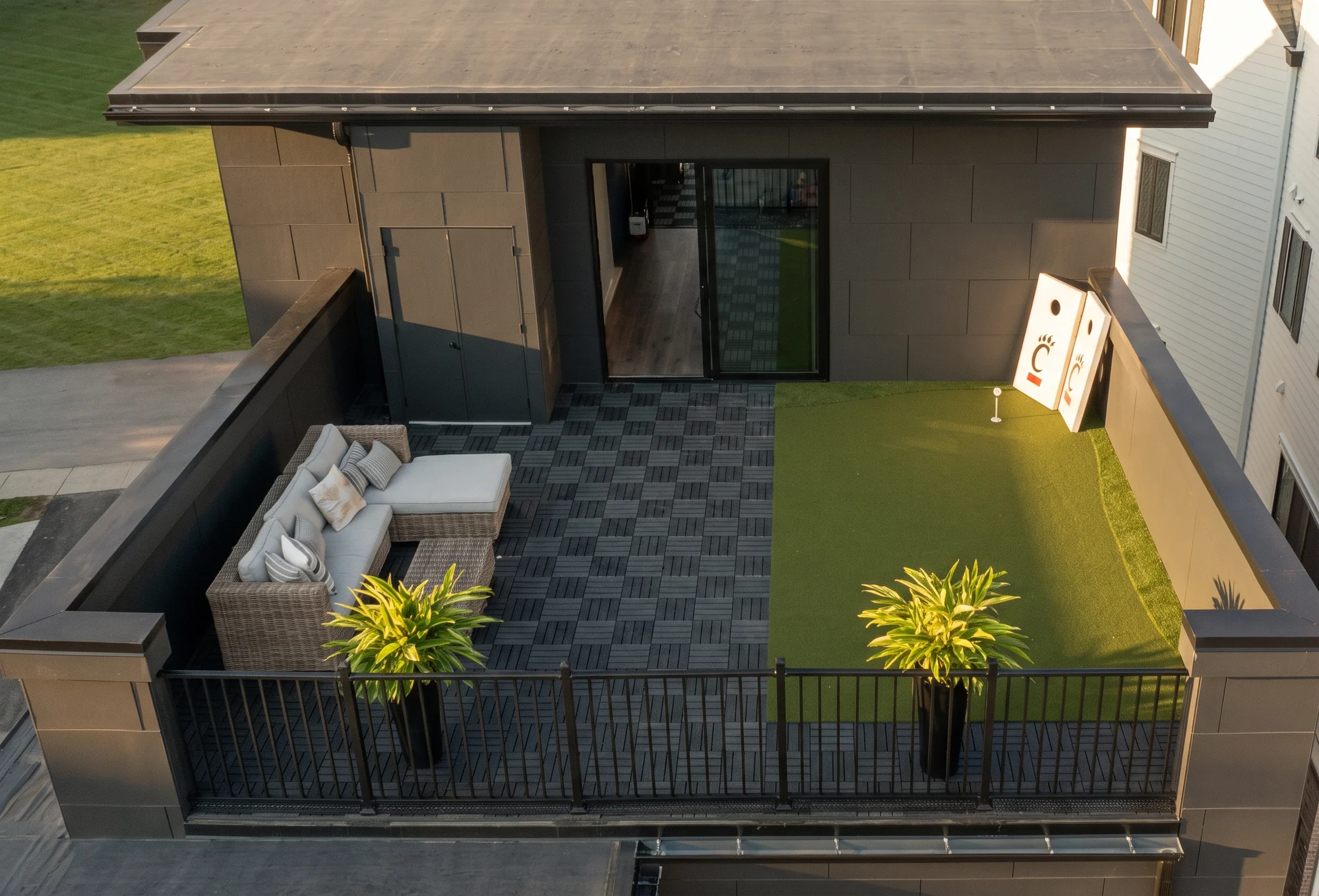 Rooftop deck on The Obsidian at Foundry Park, with a wicker sectional, a putting green and Cincinnati Bearcats cornhole boards